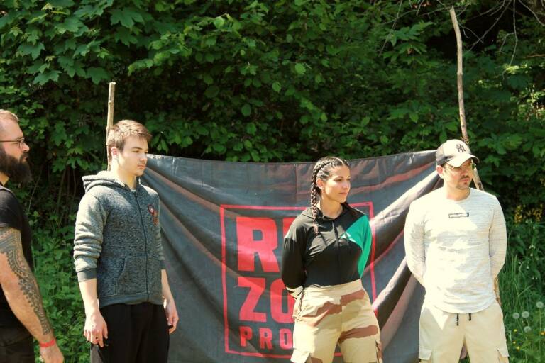 Les formateurs de Red Zone Project devant le drapeau de l'association, en forêt