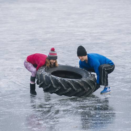 Couple flipping tyre on frozen lake